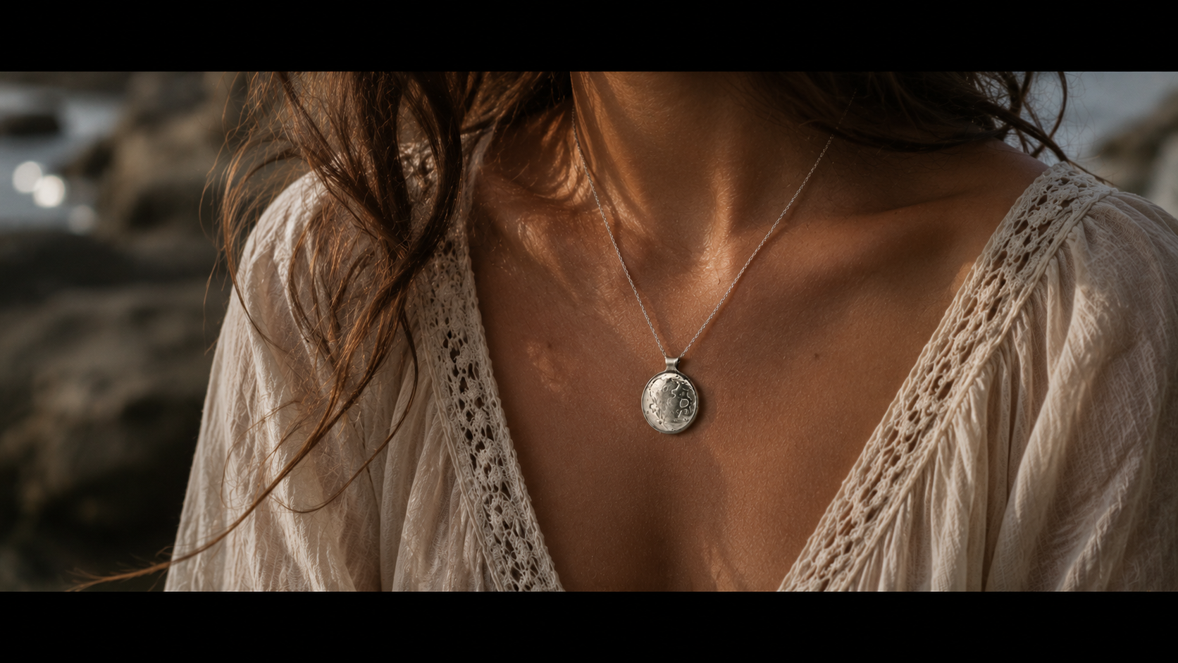 close up image of a woman in a loose white dress wearing the sterling silver moon surface necklace as part of the Lunar Ethereal collection.