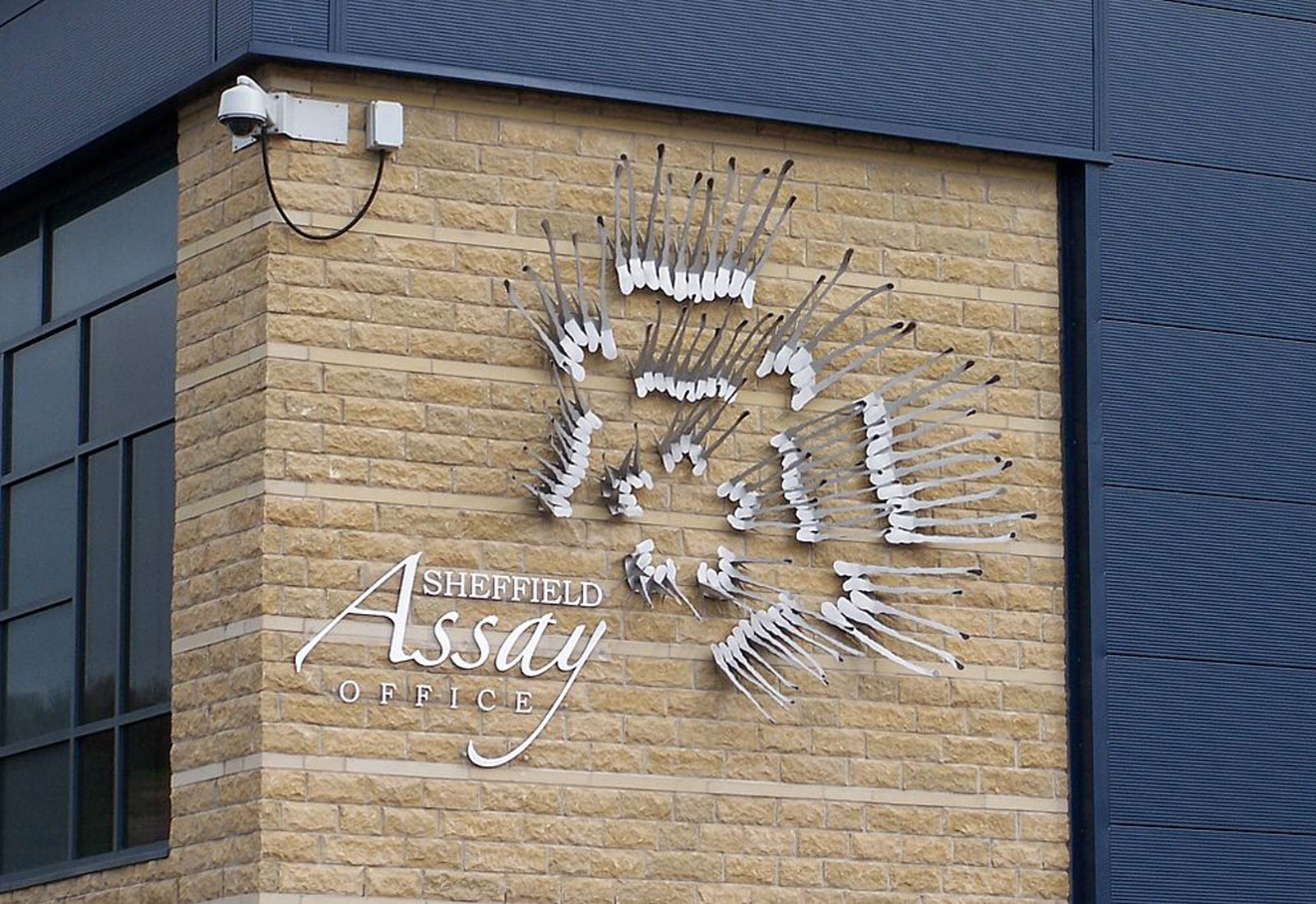 Sheffield Assay Office sign on a building facade with a blue and beige color scheme.