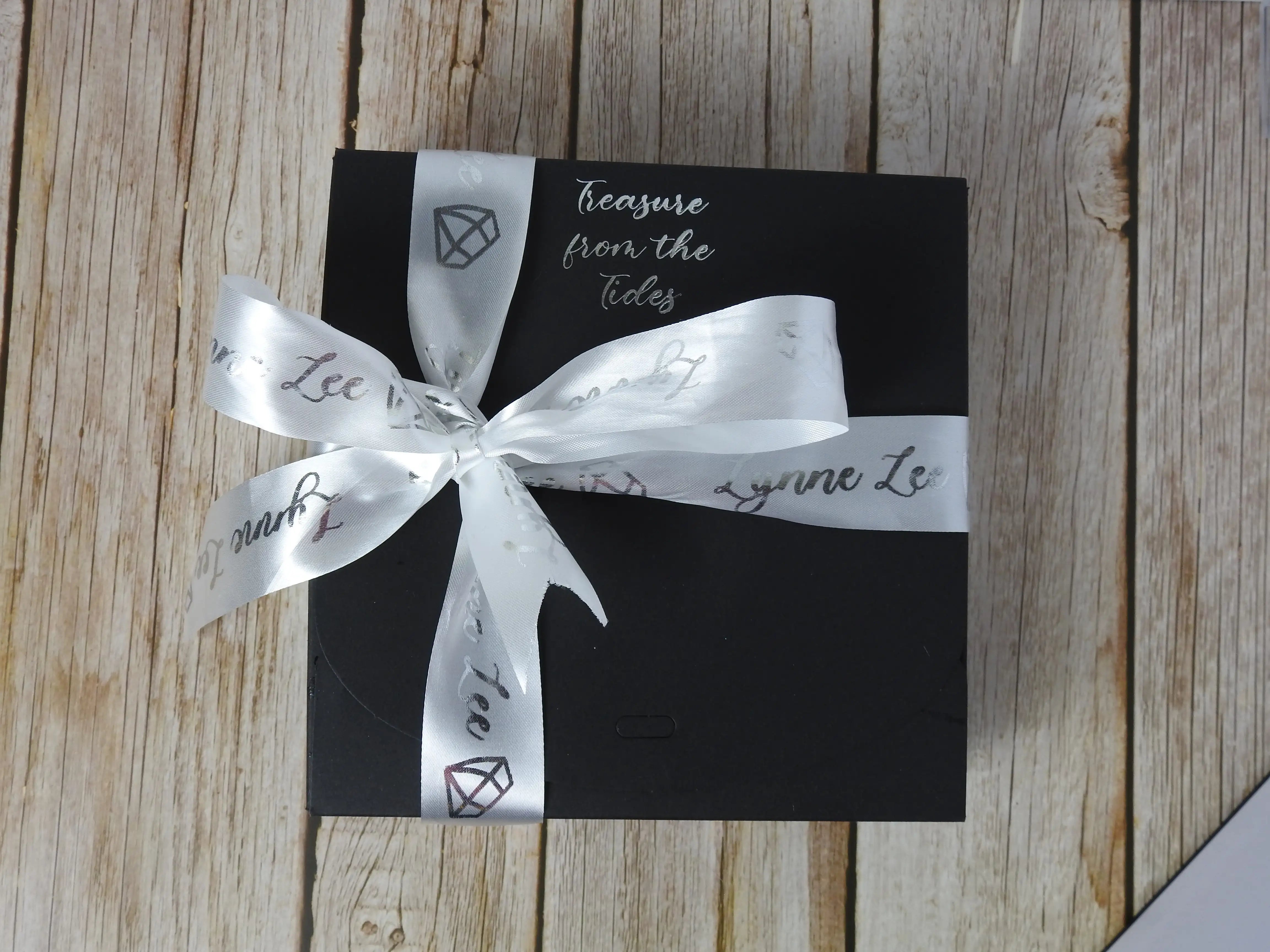 Black box with a personalised white ribbon on a wooden surface