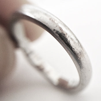 Close-up of a platinum ring with scratches on a neutral background