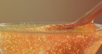 honey dripper submerged in honey, being lifted with honey dripping.