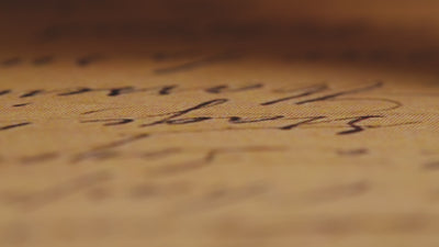 a macro video of a fountain pen writing across golden coloured parchment paper.